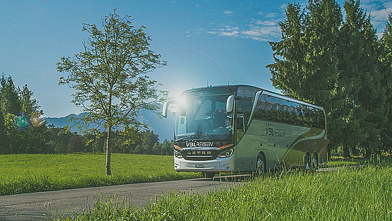 Reisecar von VBL Reisen auf einer Landstrasse zwischen grünen Wiesen.