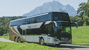 Der TOP-CLASS SETRA 531 Doppelstöcker auf einem Landweg zwischen grünen Wiesen und dem Pilatus im Hintergrund.