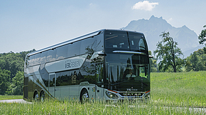 Der TOP-CLASS SETRA S 531 DT auf einem Landweg zwischen grünen Wiesen und dem Pilatus im Hintergrund.